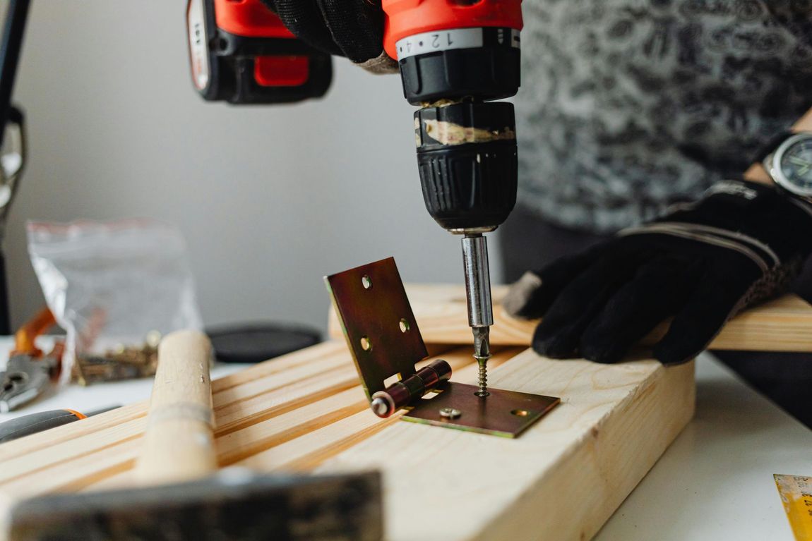 Power drill securing a hinge, representing residential property renovations and construction loan escrow tracking.