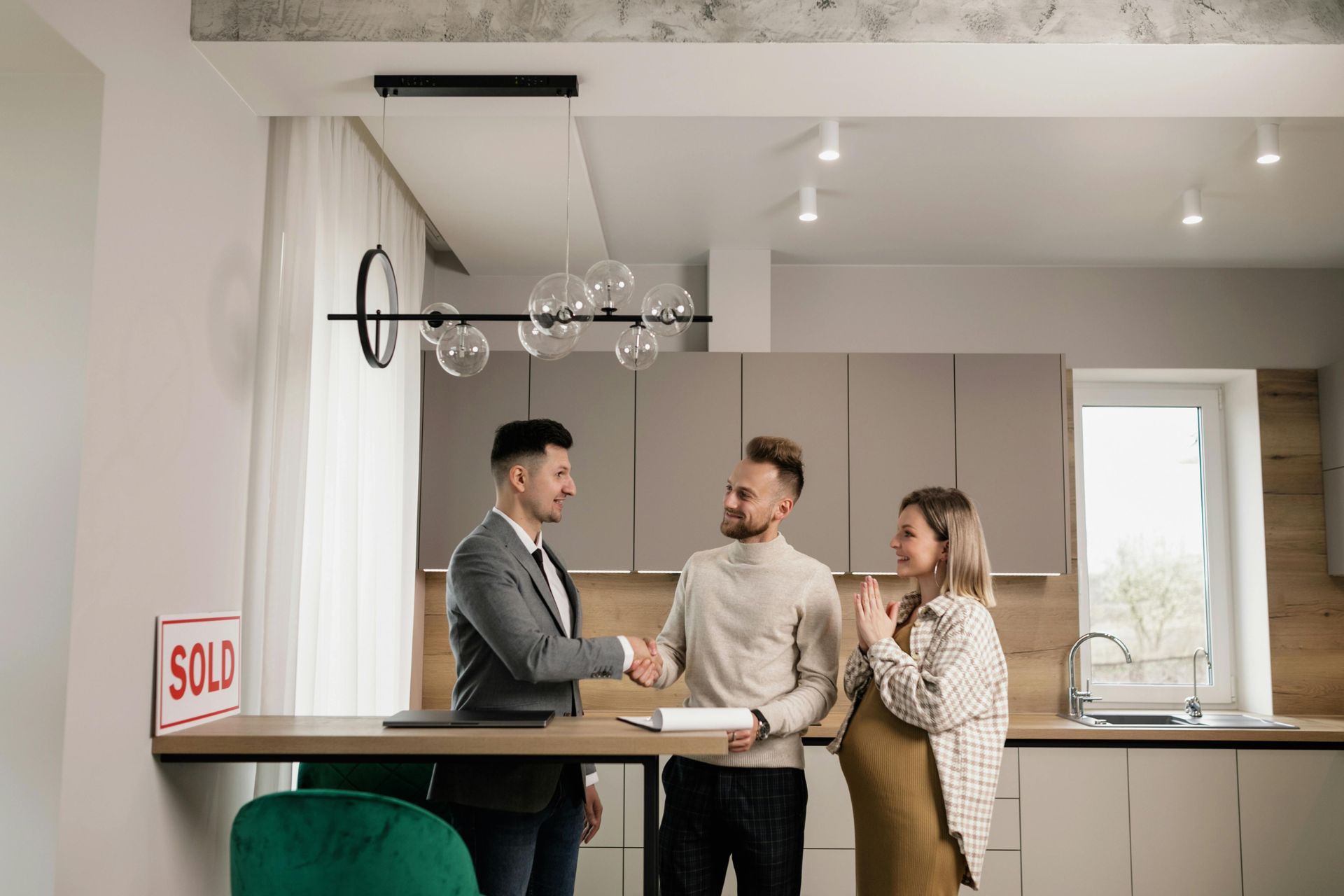 Real estate professional shaking hands with homebuyers, representing a successful settlement process and final deed delivery.