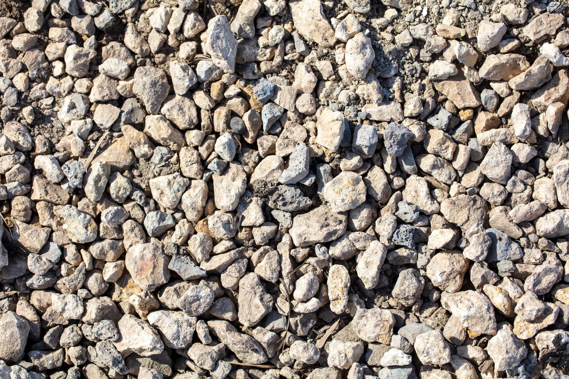 Gravel surface with various sized gray, beige, and brown rocks.