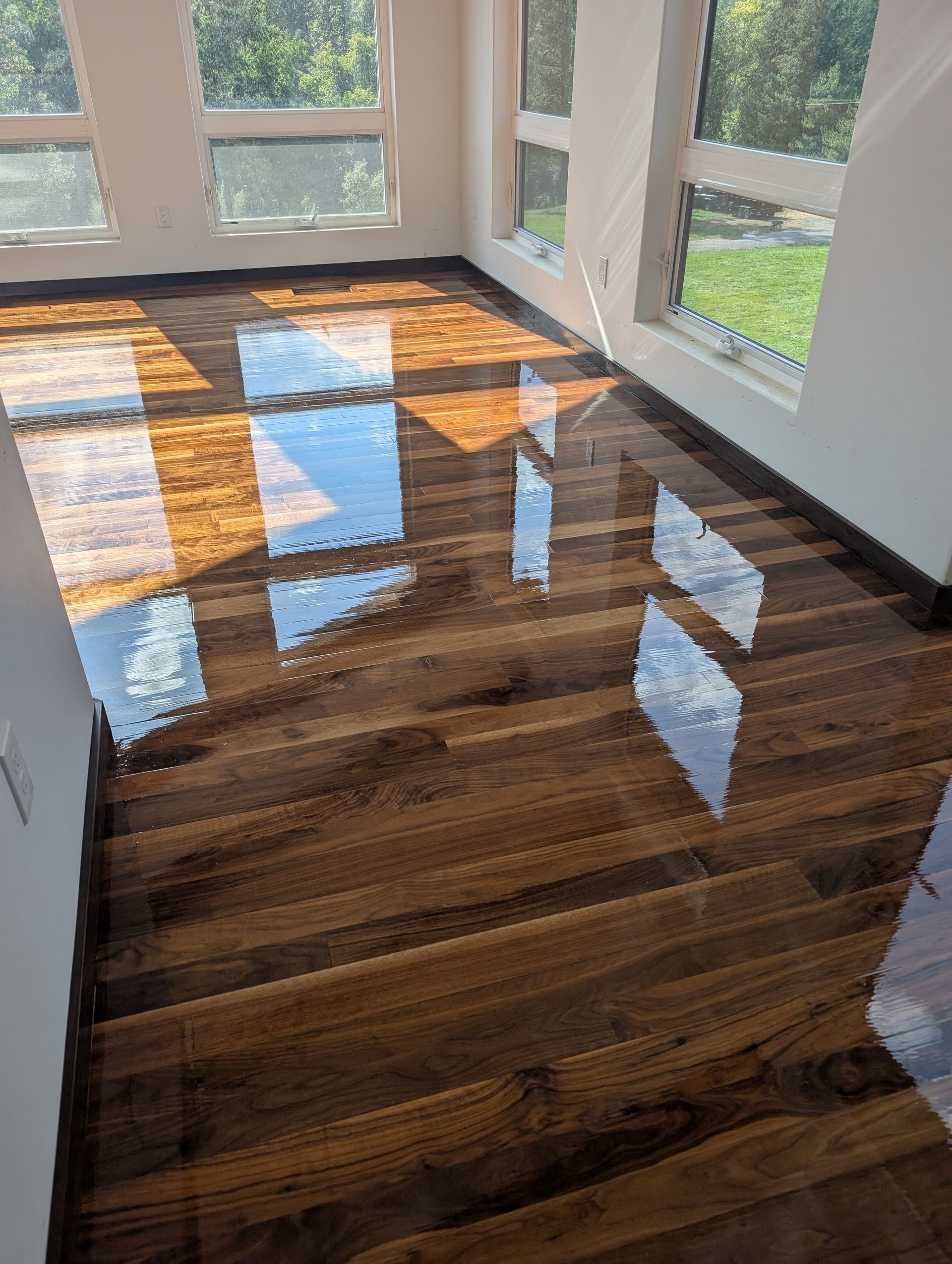 Electric floor sander on a wooden floor near a window, polishing the surface.