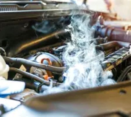 Car engine steaming under the hood, suggesting overheating or a mechanical problem