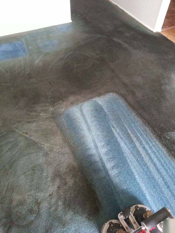 A vacuum cleaner is cleaning a dirty carpet in a living room.