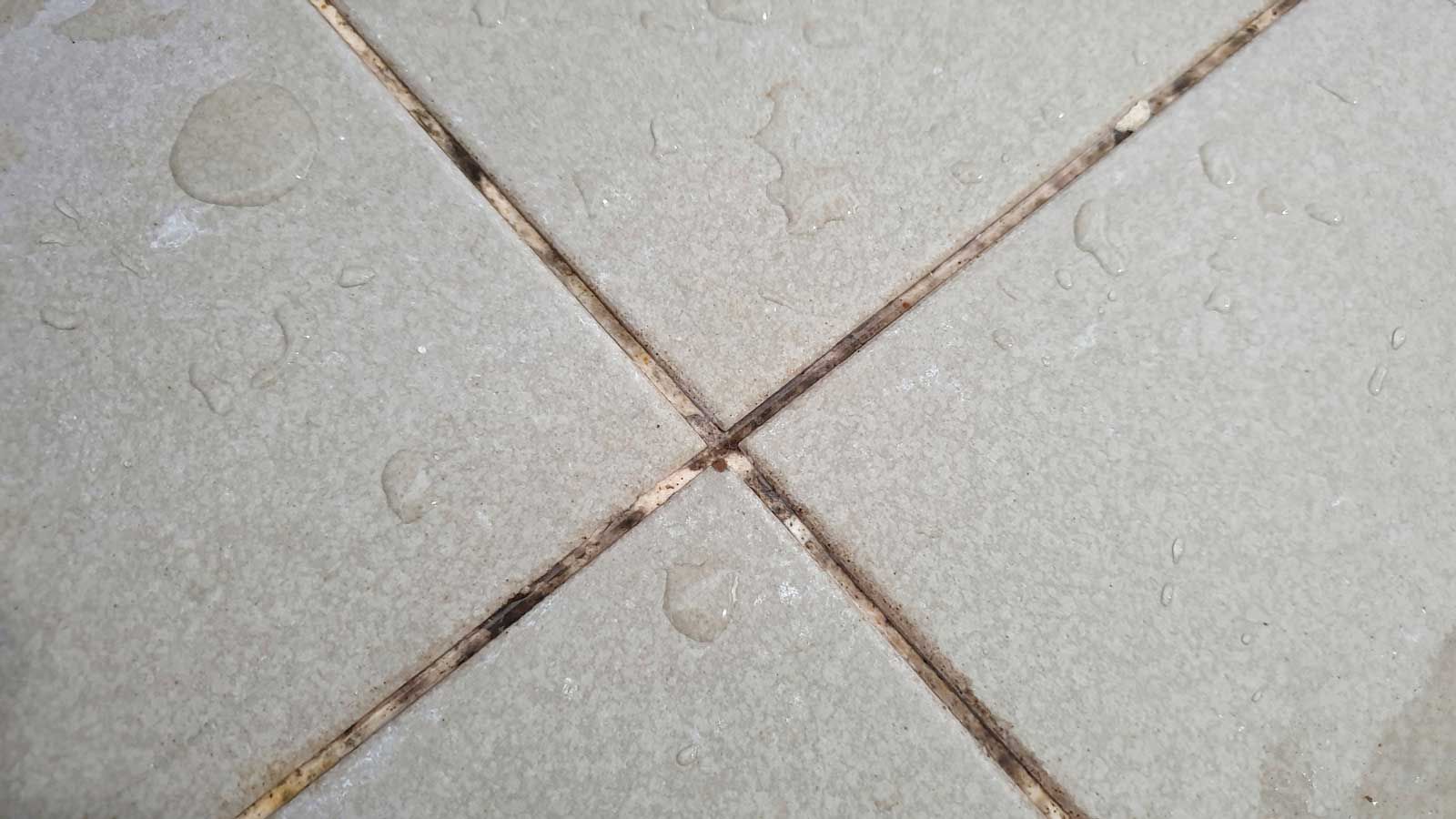 A close up of a tile floor with water drops on it.