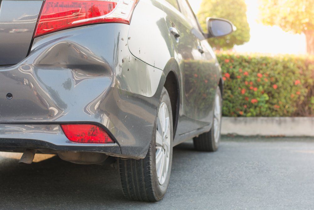 A Car with A Damaged Bumper Is Parked on The Side of The Road — East Maitland Body Repairs in East Maitland, NSW