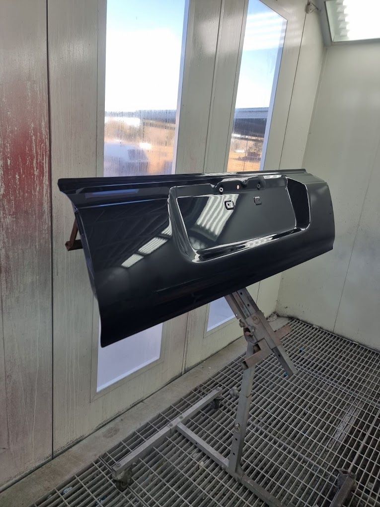 A Black Car Door Is Sitting on A Stand in A Paint Booth — East Maitland Body Repairs in Maitland, NSW