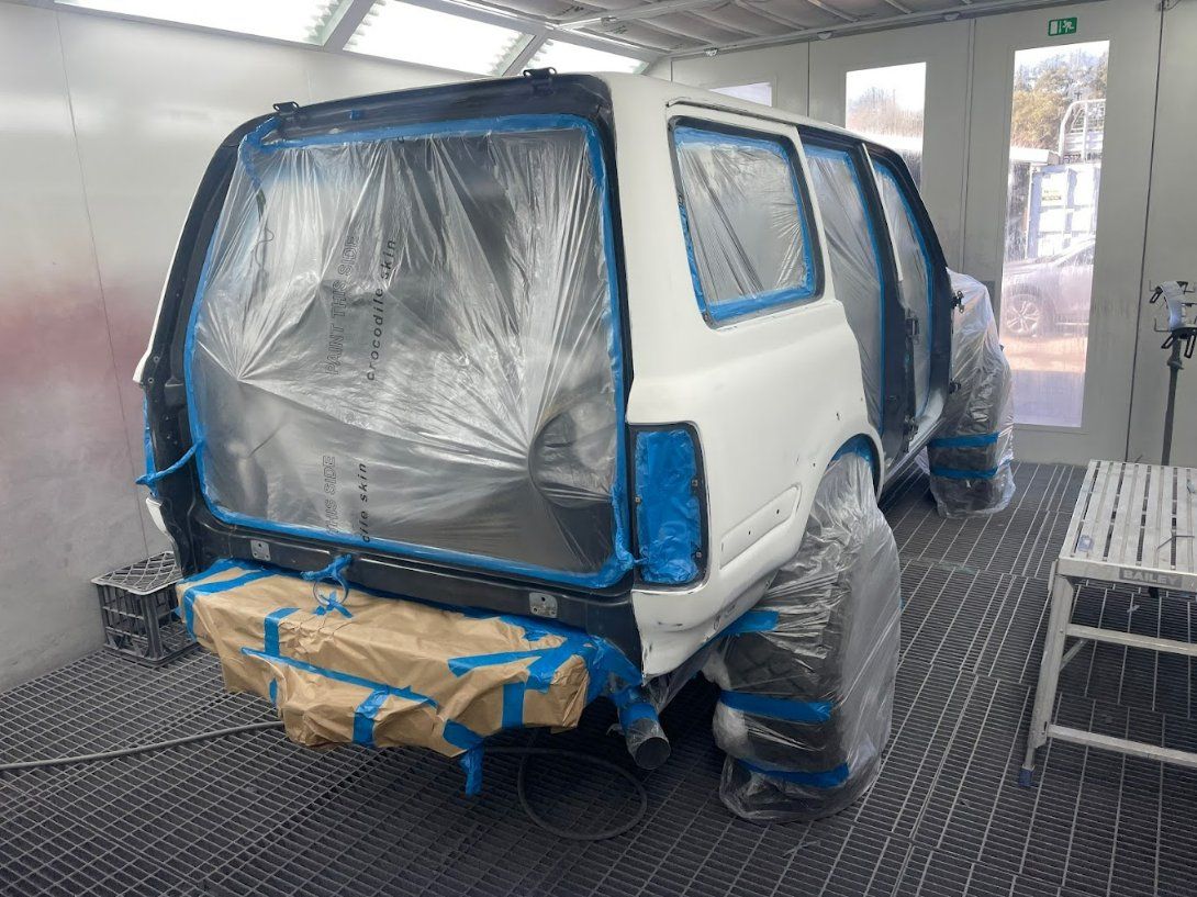 A White SUV Is Being Painted in A Paint Booth — East Maitland Body Repairs in East Maitland, NSW