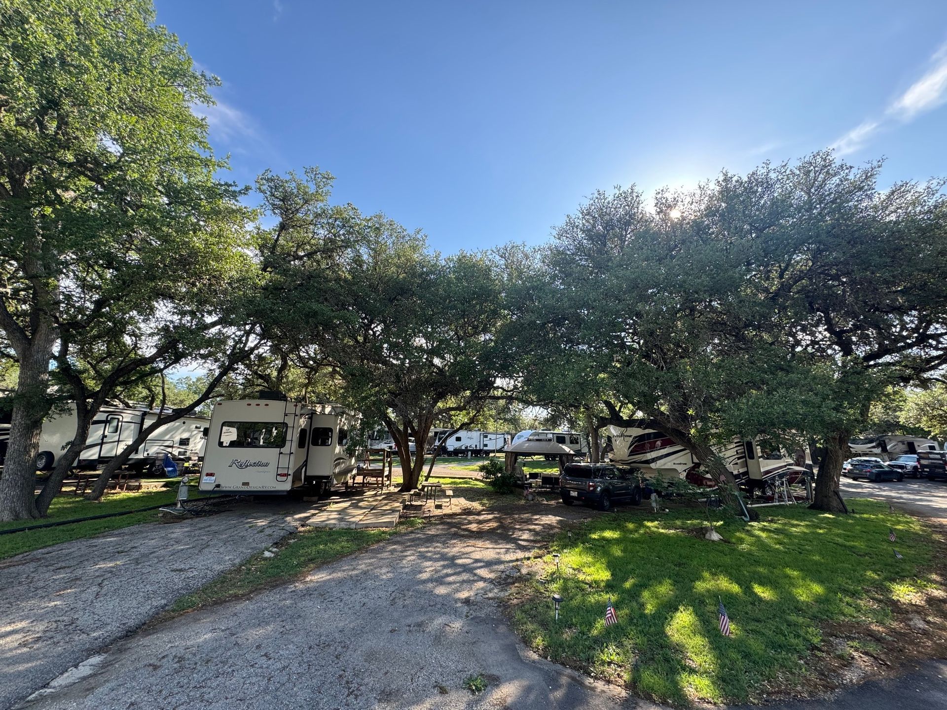 A row of rvs parked in a lot surrounded by trees.