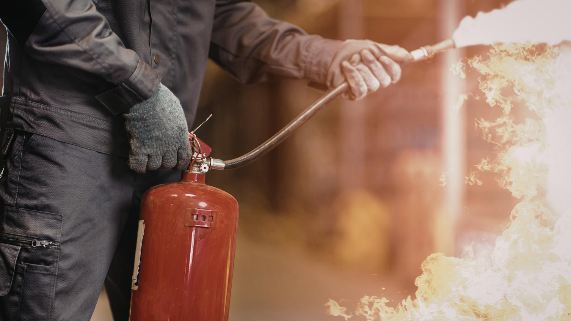 Person holding a red fire extinguisher spraying foam at flames indoors