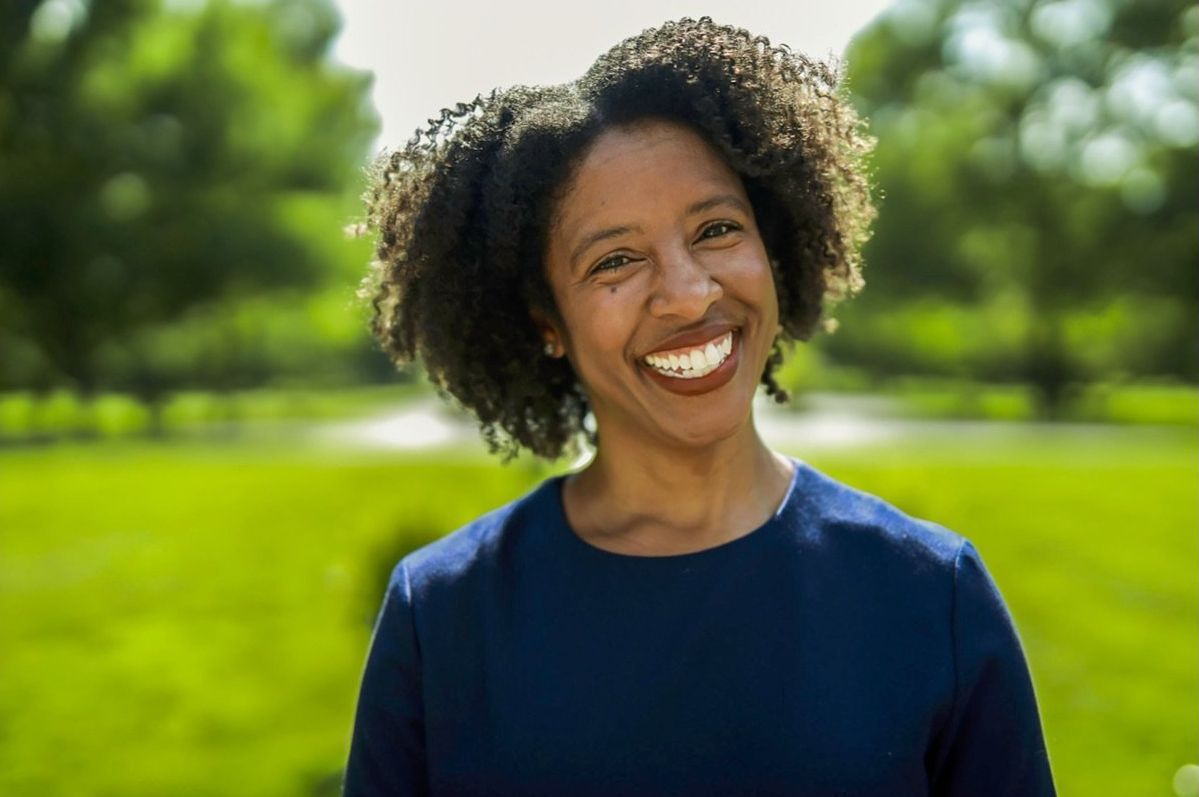 a woman in a blue shirt is smiling in front of a green field .
