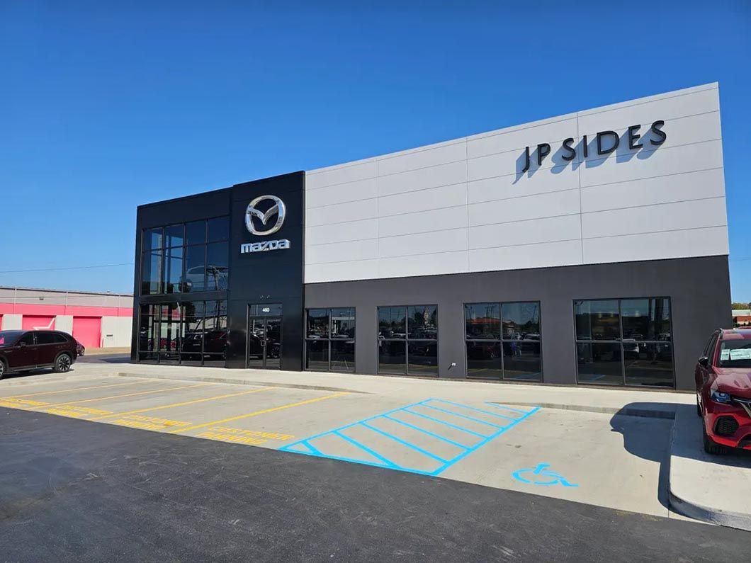 A mazda car dealership with a handicapped parking spot in front of it.