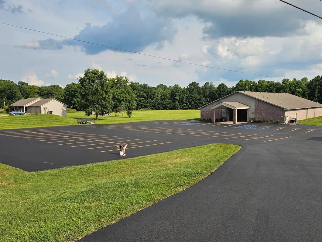 A house is sitting in the middle of a grassy field next to a road.