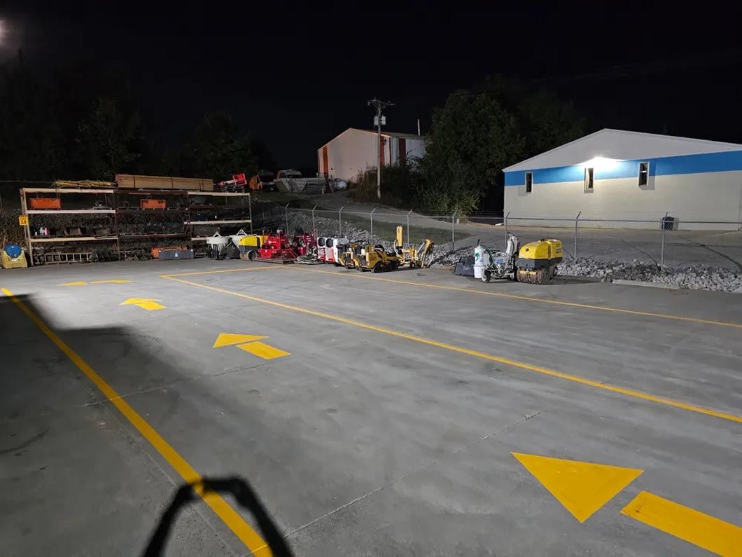 A row of trucks are parked in a parking lot at night.