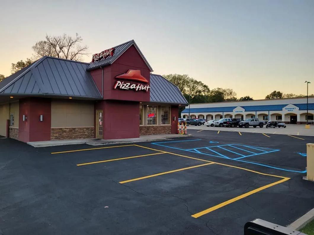 A pizza hut restaurant with a parking lot in front of it.