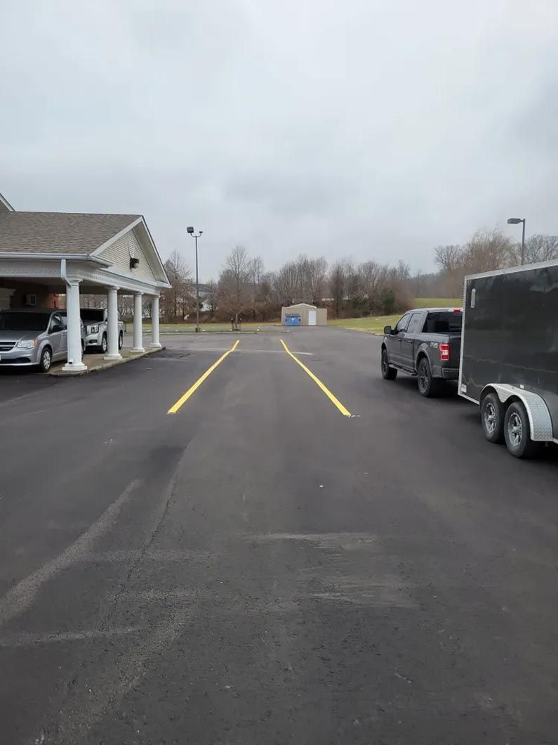 A parking lot with cars and trailers parked in front of a building.