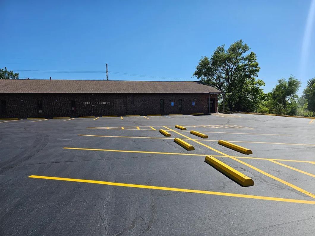 A parking lot with yellow curbs and a building in the background.