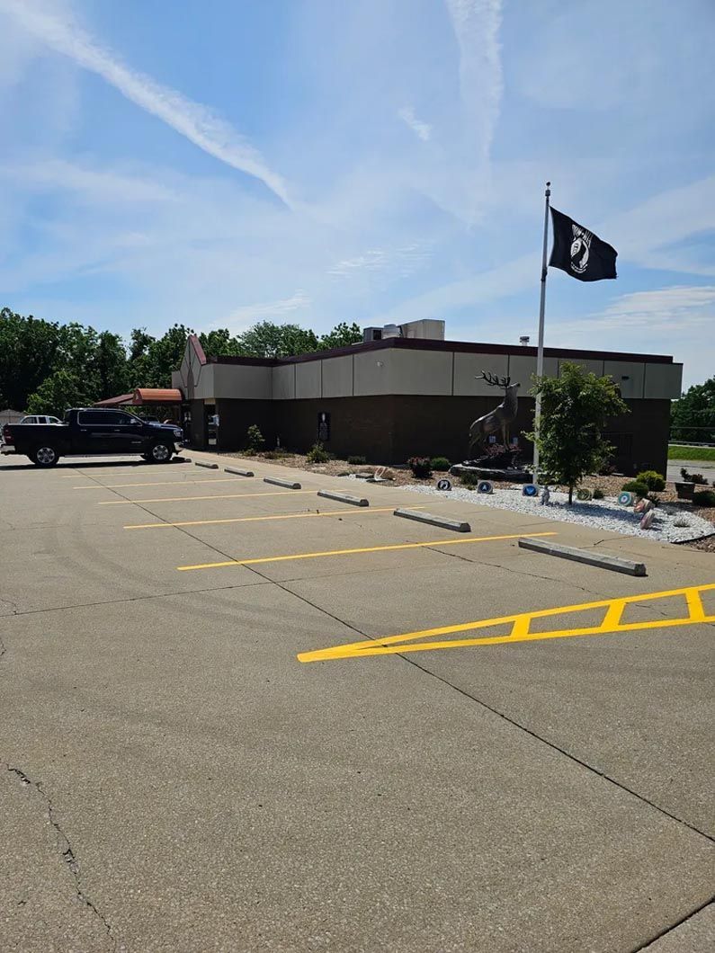 A black truck is parked in a parking lot in front of a building.