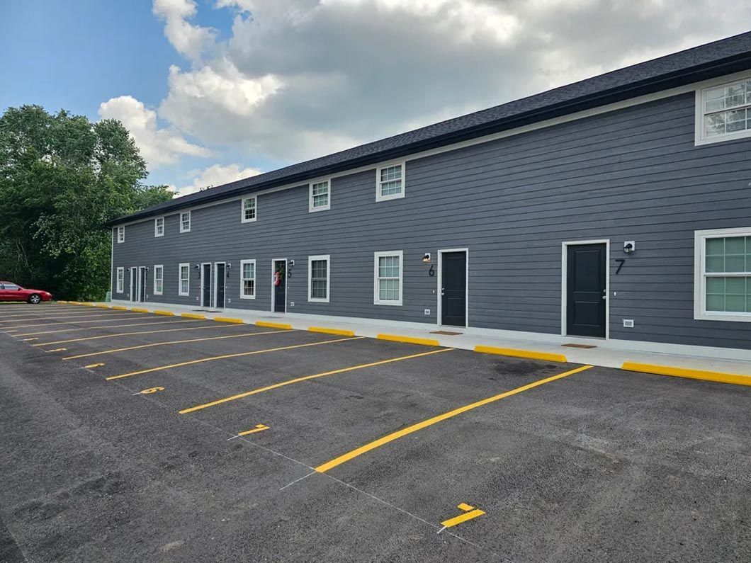 A large apartment building with a parking lot in front of it.
