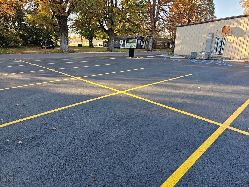 A parking lot with yellow lines and a building in the background.