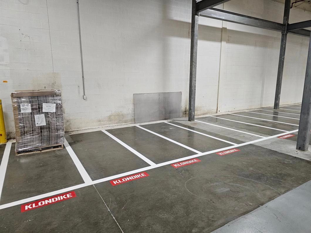 A warehouse with white lines on the floor and a pallet in the background.