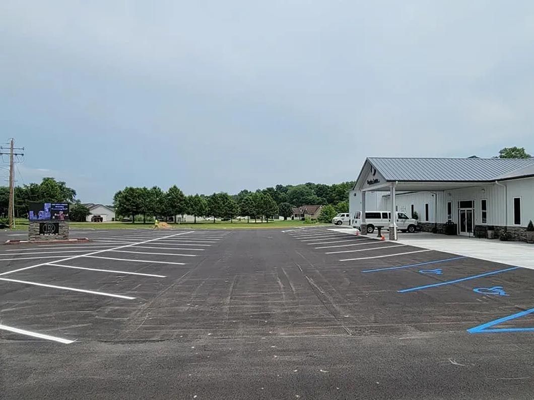 A large parking lot with a white building in the background.