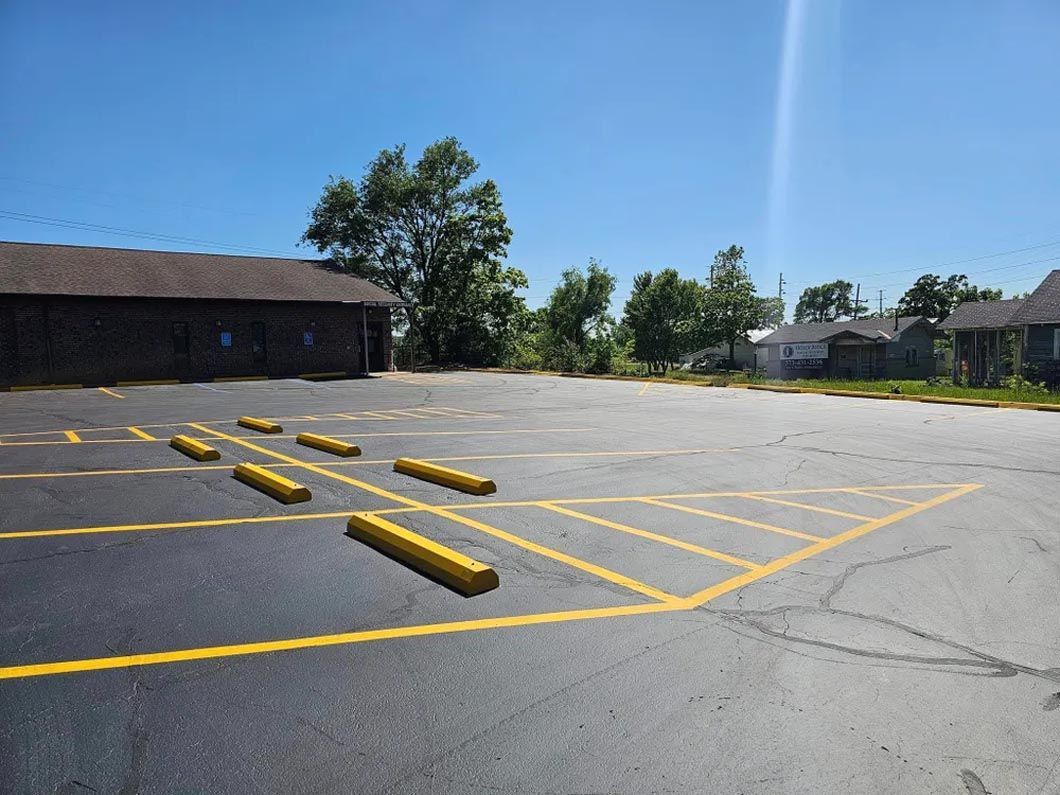 A parking lot with yellow curbs and a building in the background.