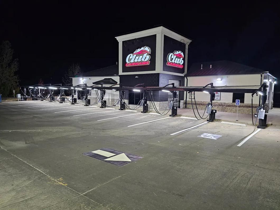 A car wash is lit up at night in a parking lot.