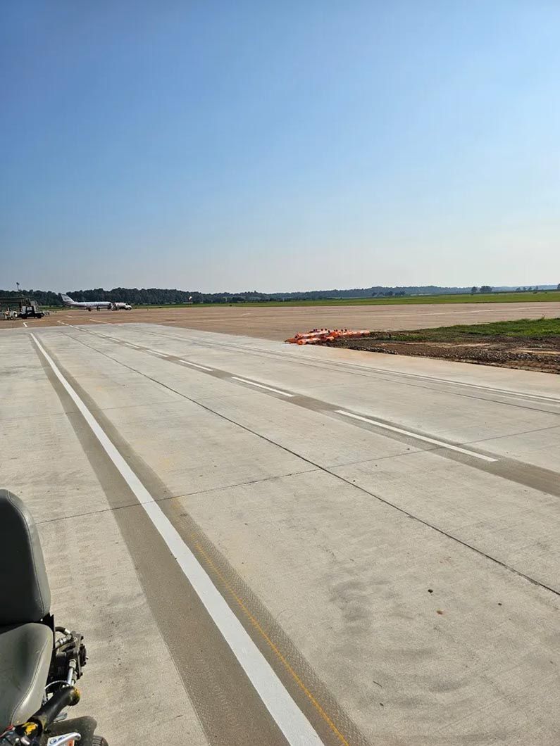 A motorcycle is parked on the side of a road next to an airport runway.