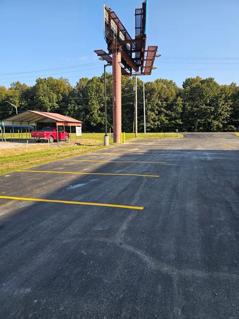 A red truck is parked in a parking lot next to a large billboard.