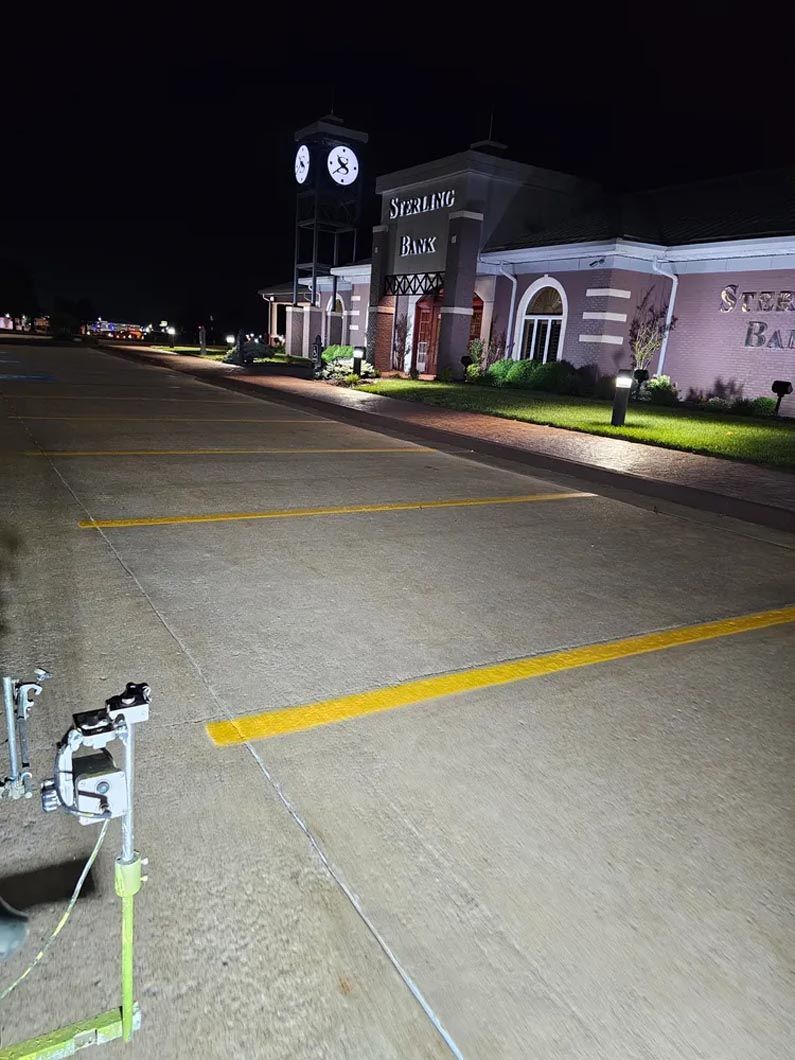 A trailer is parked in a parking lot in front of a building at night.