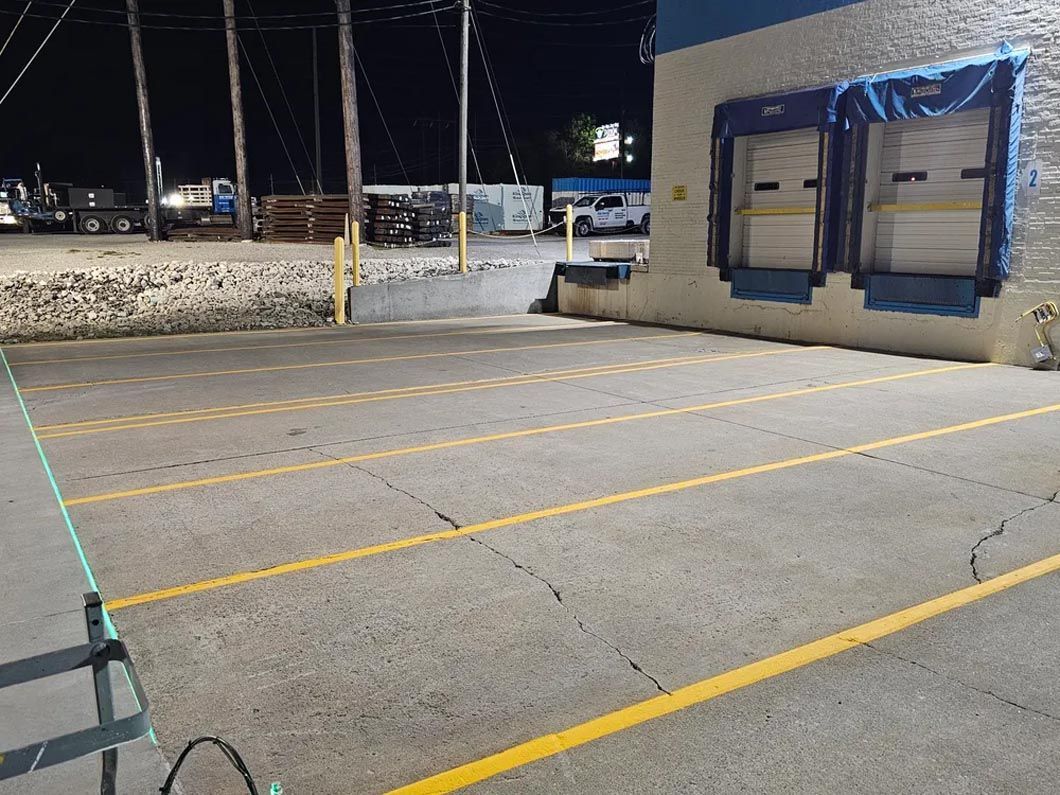 A parking lot with yellow lines and a building in the background.