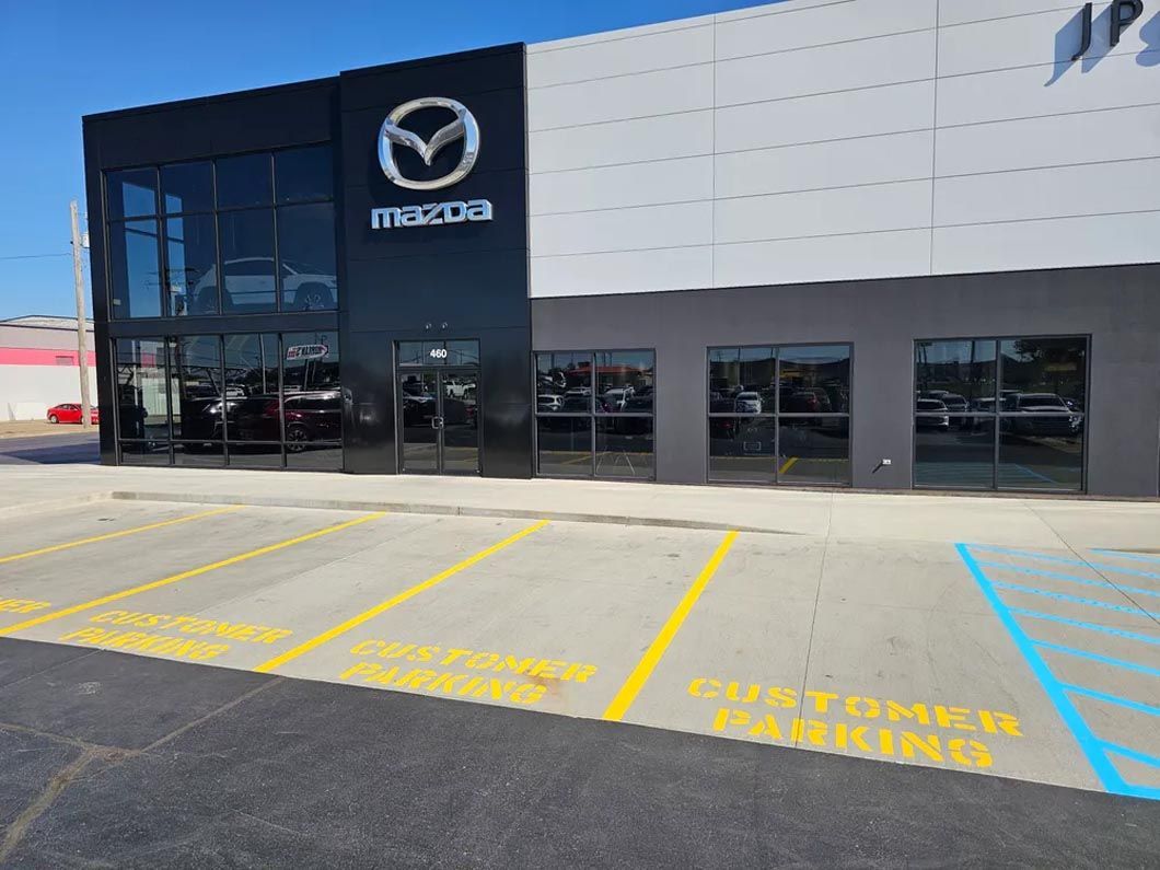 A mazda car dealership with a parking lot in front of it.