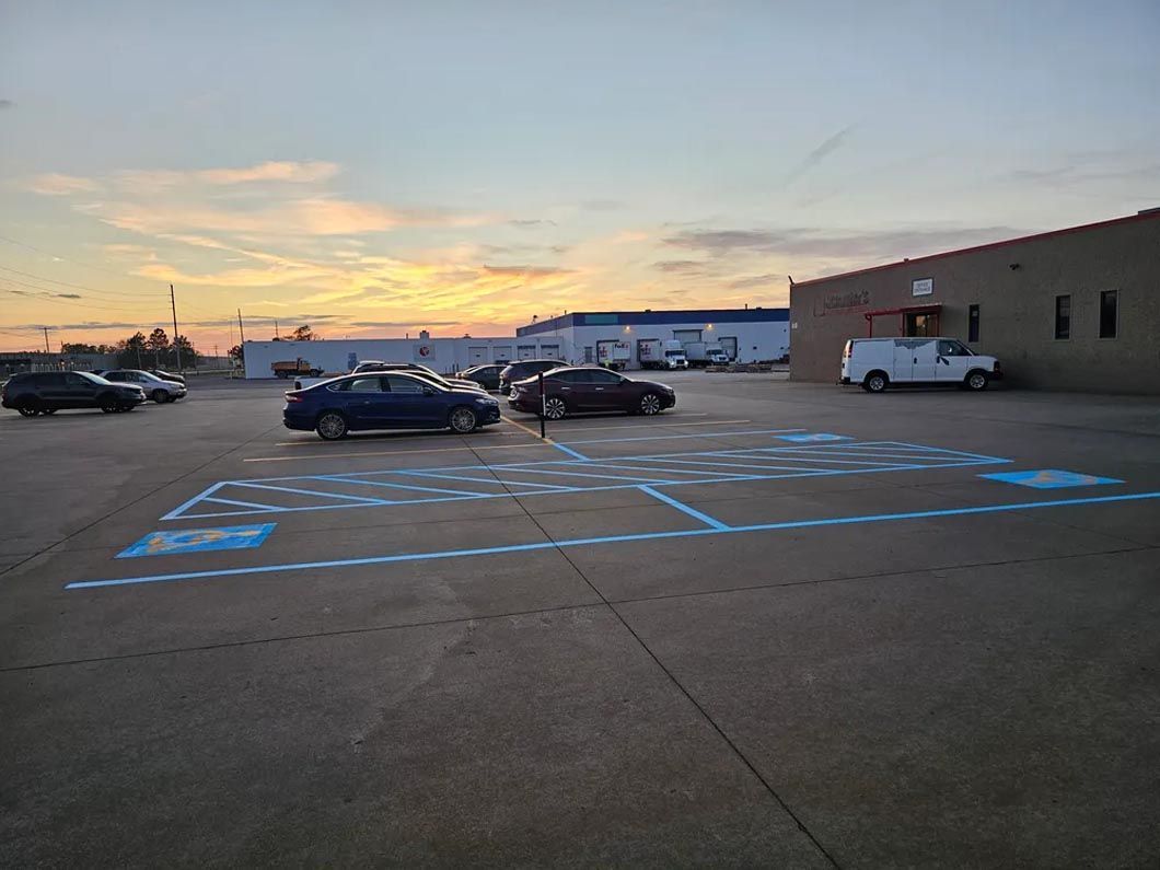 A parking lot with cars parked in front of a building at sunset.