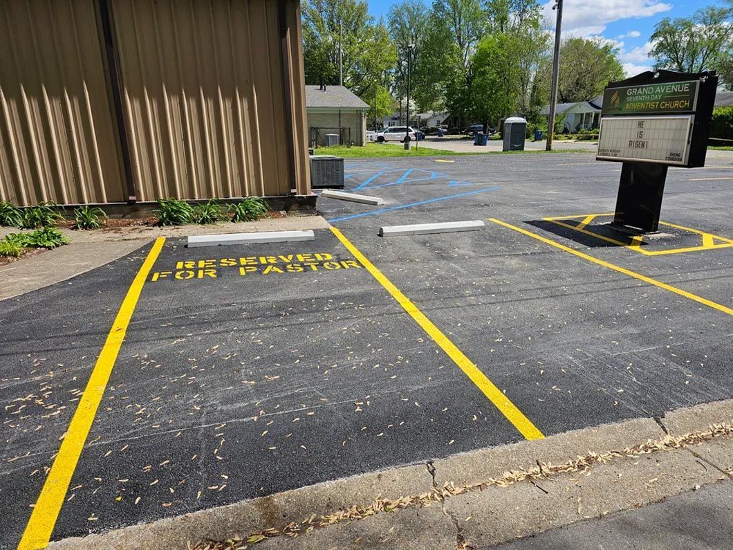 A parking lot with yellow lines on it and a building in the background.