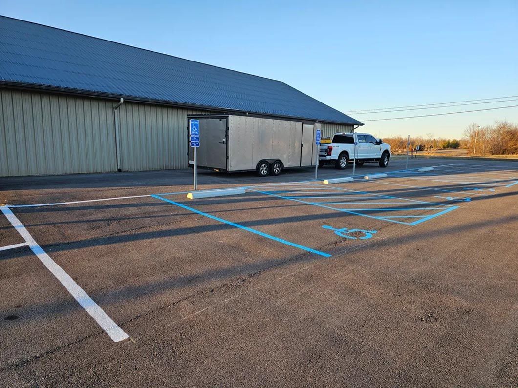 A truck and trailer are parked in a handicapped parking spot in front of a building.
