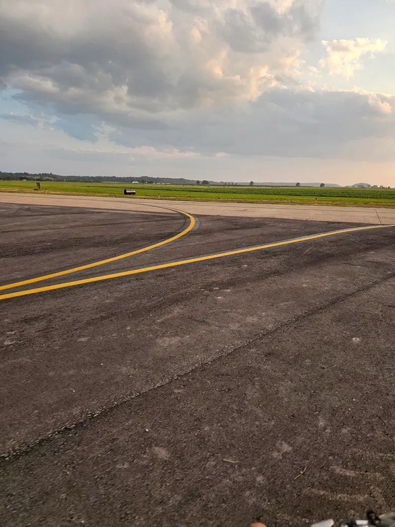A runway with a yellow line on it and a cloudy sky in the background