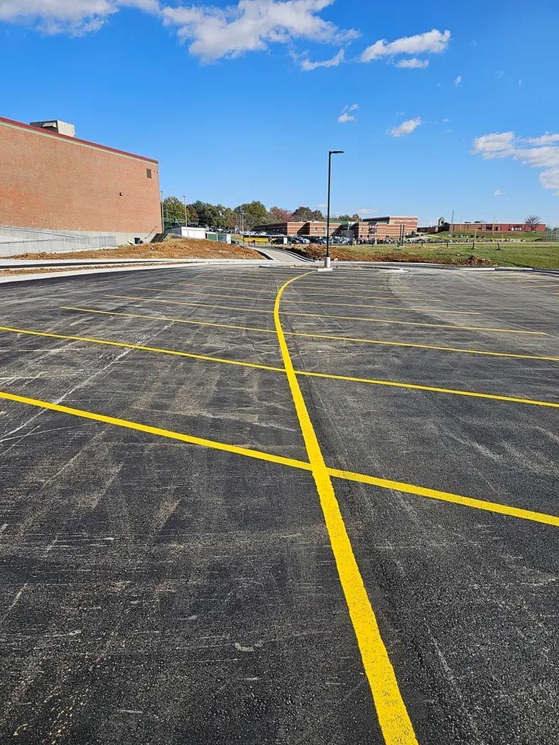 A parking lot with yellow lines and a building in the background.
