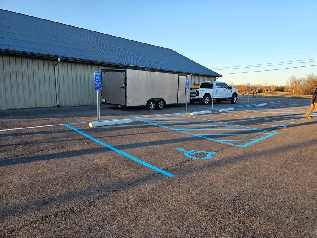 A white truck is parked in a handicapped parking spot in front of a building.
