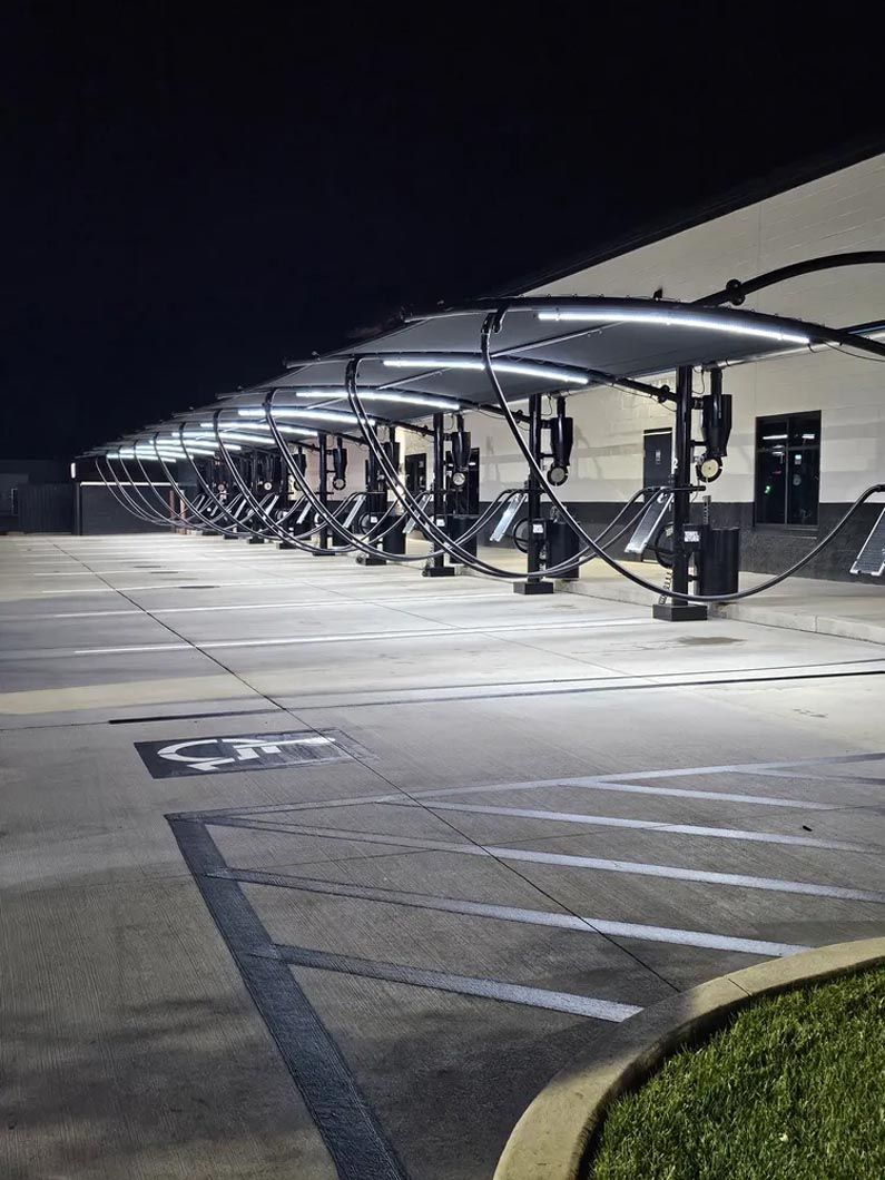 A parking lot with a row of covered parking spaces at night.