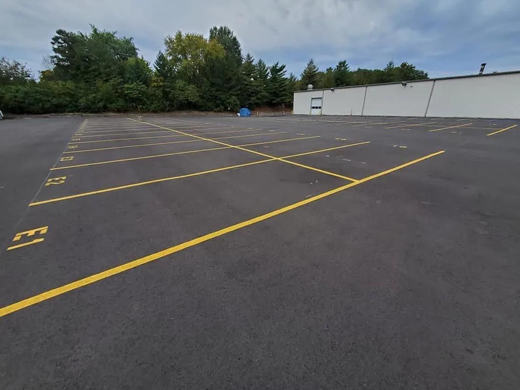 A parking lot with yellow lines and a white building in the background.
