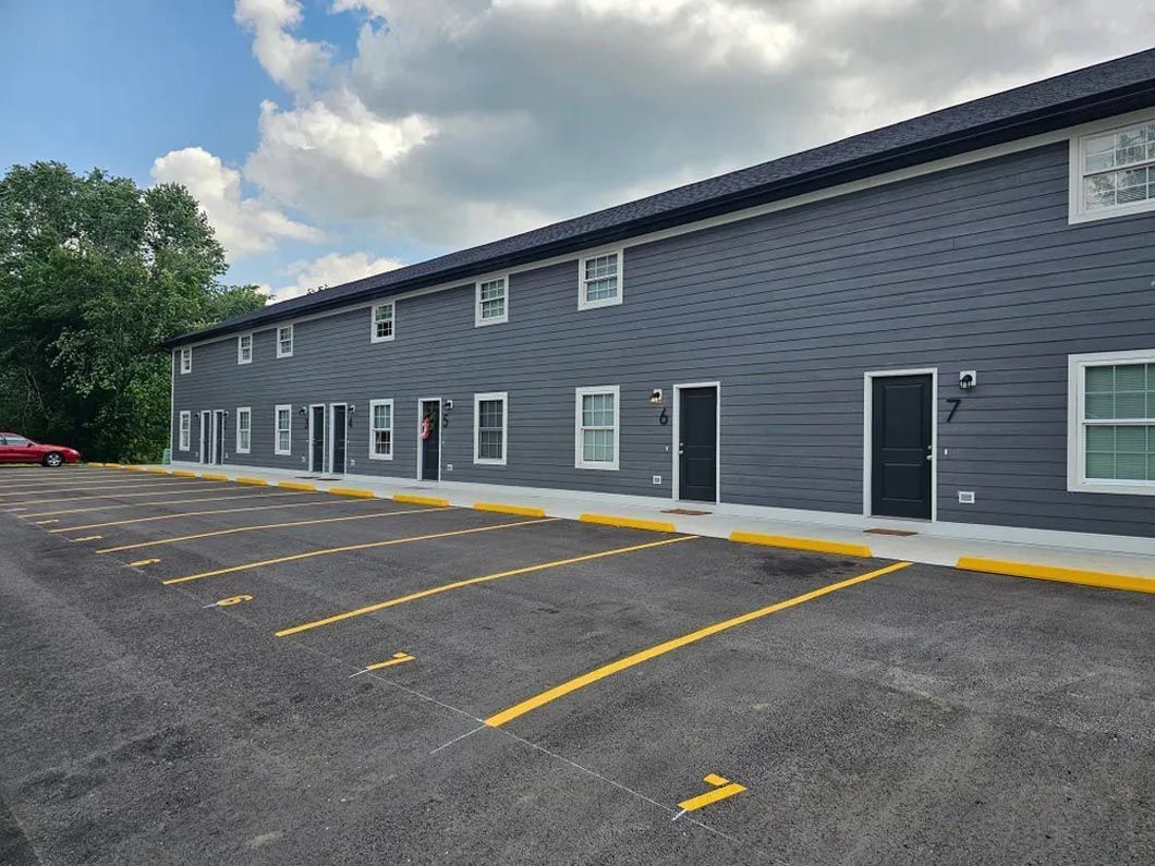 A large apartment building with a parking lot in front of it.