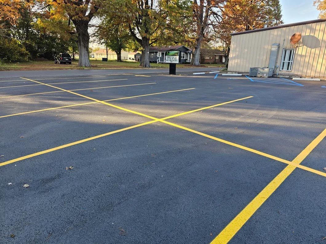 A parking lot with yellow lines and a building in the background.