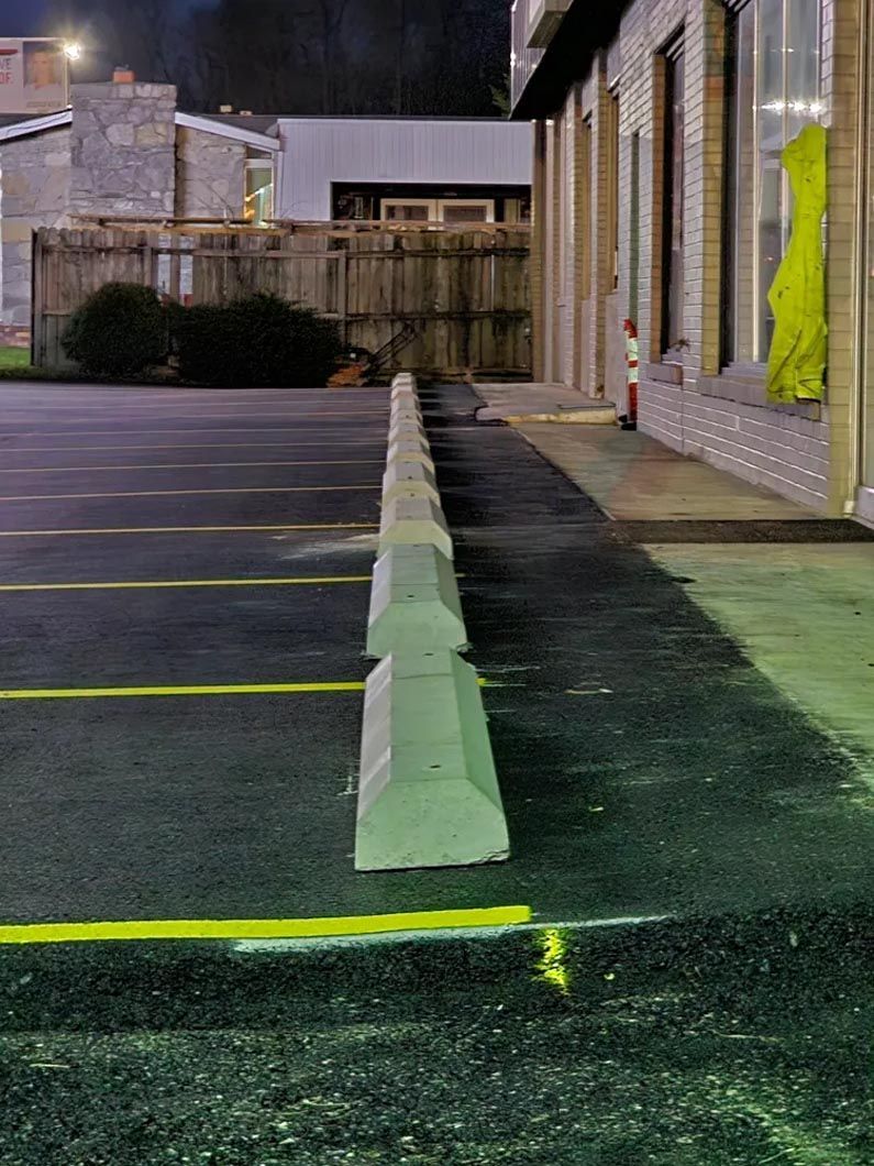 A row of parking blocks in a parking lot next to a building.