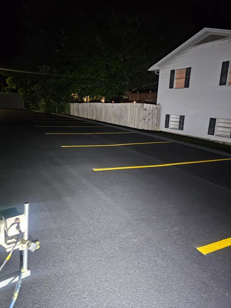 A white house is behind a parking lot at night.