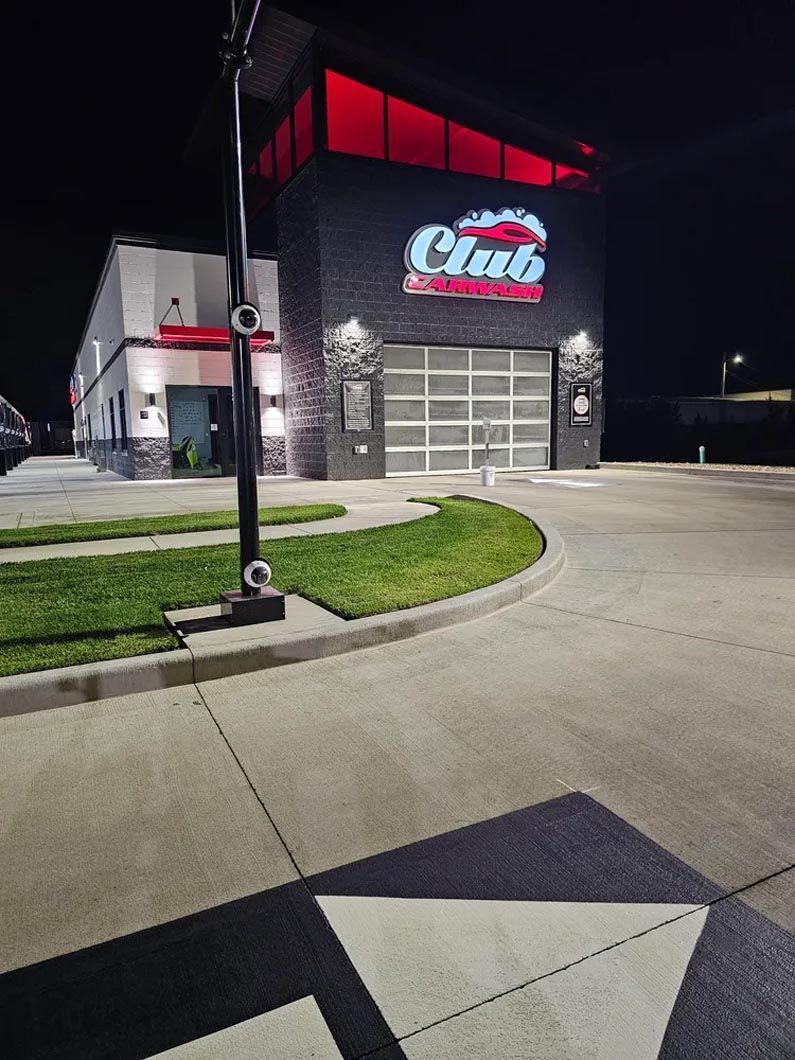 A club car wash is lit up at night with red lights.