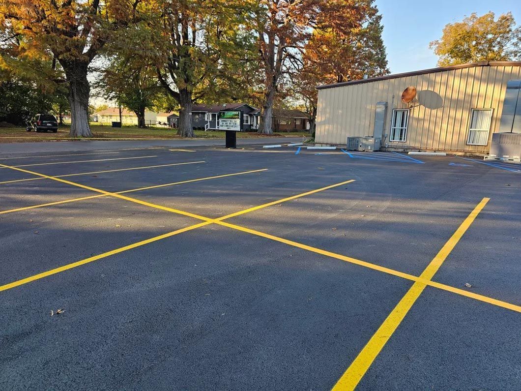 A parking lot with yellow lines and a building in the background