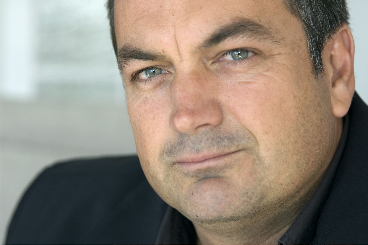 Man with graying hair and blue eyes looks toward the viewer.