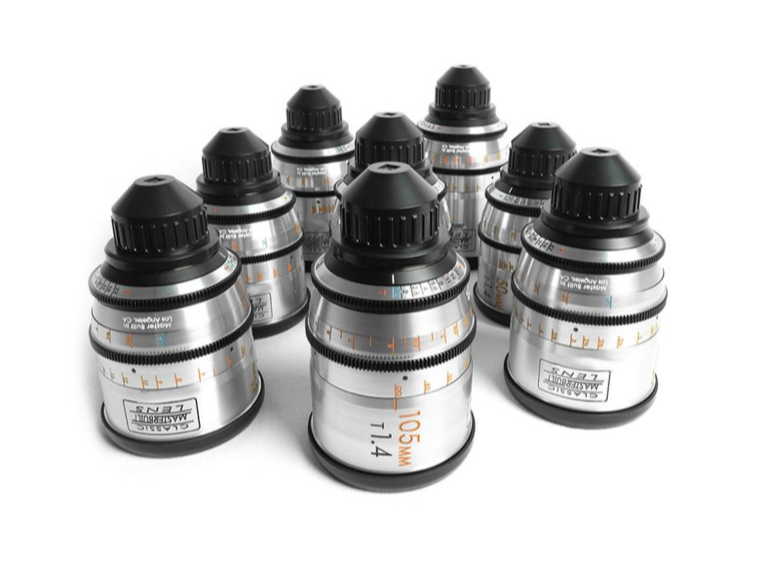 Nine silver camera lenses with black tops and focus rings on a white surface.