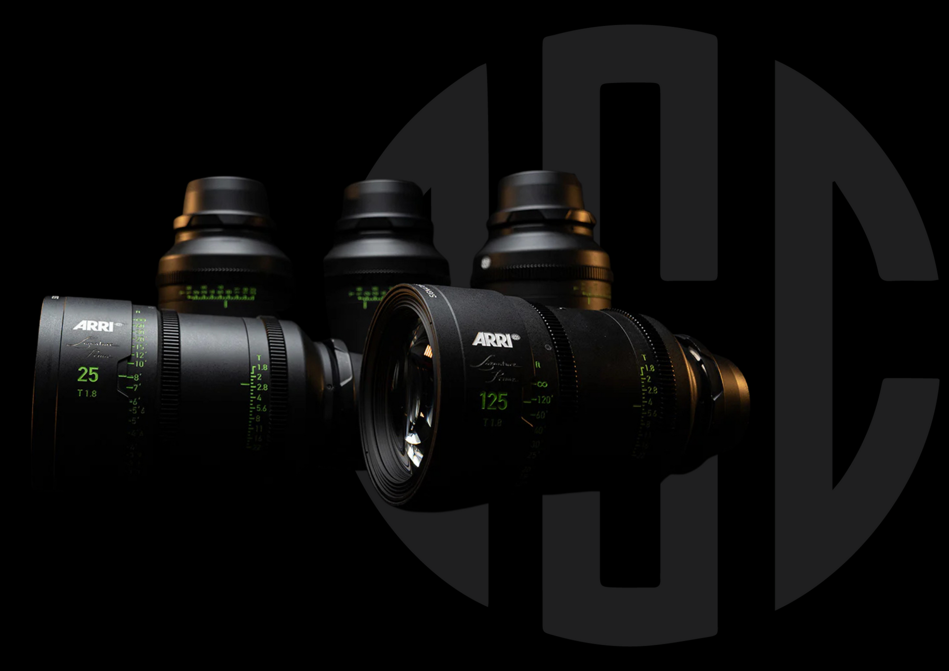 Four black camera lenses arranged against a black background. The lenses have green markings.
