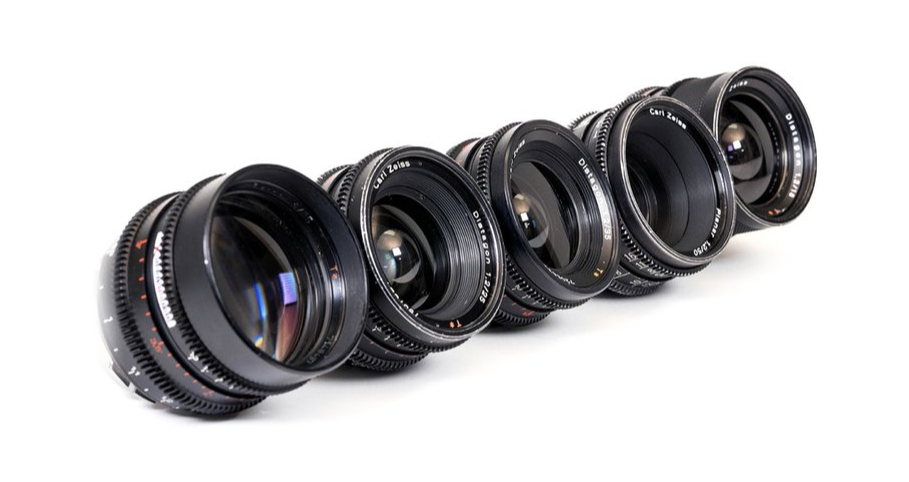 Five black camera lenses arranged diagonally on a white surface.
