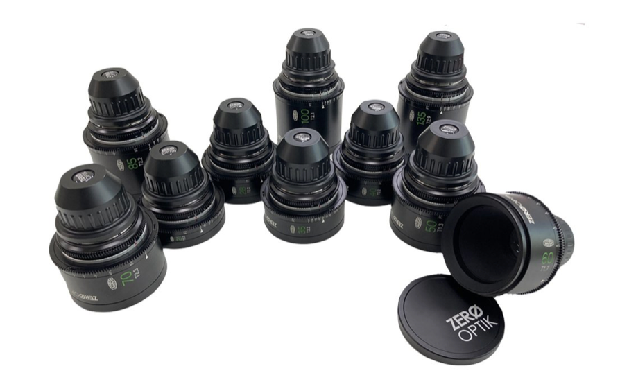 Ten black Zero Optik camera lenses, with a lens cap, arranged on a white surface.